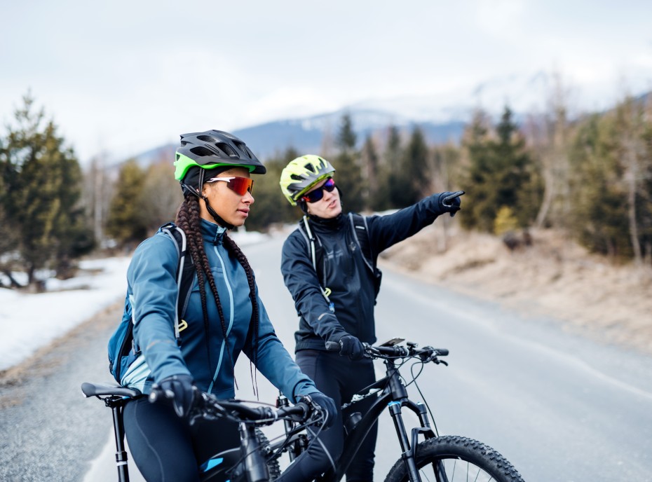 Zwei Radfahrerinnen mit Sportbrillen in kühler Landschaft sehen sich die Umgebung an